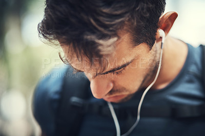 Buy stock photo Closeup shot of a handsome young man listening to music while out for a hike in the mountains