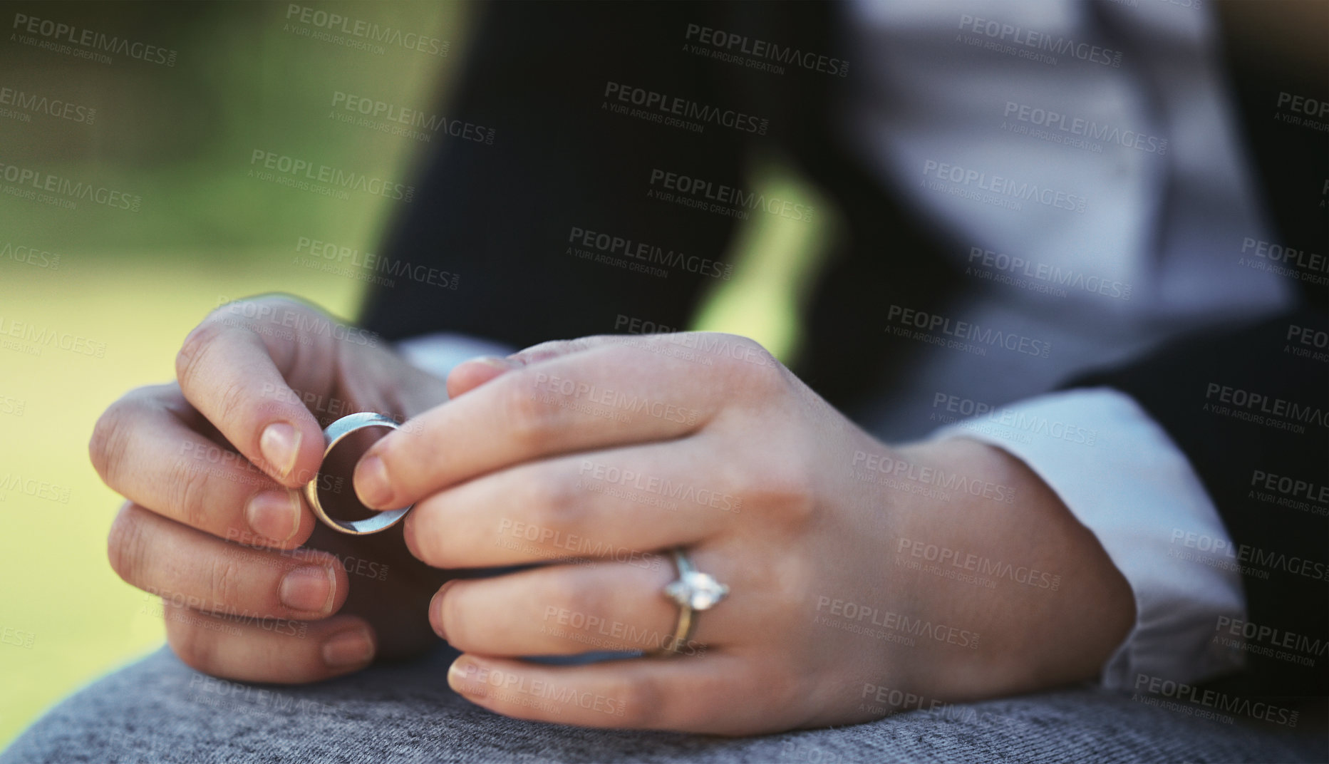 Buy stock photo Closeup shot of an unrecognizable businesswoman holding a wedding ring while sitting in a public park