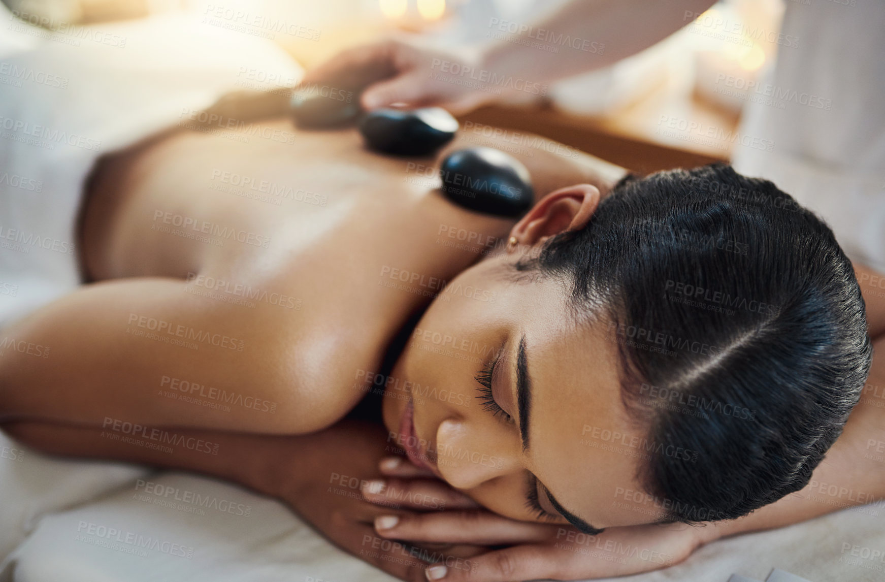 Buy stock photo Woman, relax and sleeping for back massage, skincare or relaxation at indoor beauty spa on bed. Female relaxing with hands of masseuse applying hot rocks for physical therapy or treatment at resort