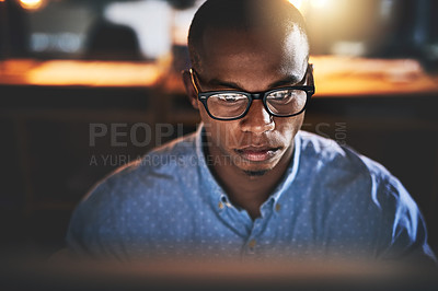 Buy stock photo Cropped shot of a handsome young businessman using a computer during a late night in a modern office