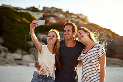 Buy stock photo Shot of three friends taking a selfie at the beach
