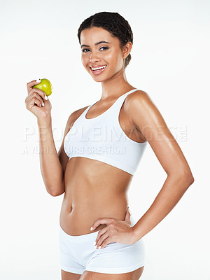 Buy stock photo Portrait of an attractive young woman holding a apple in her hand while standing against a white background