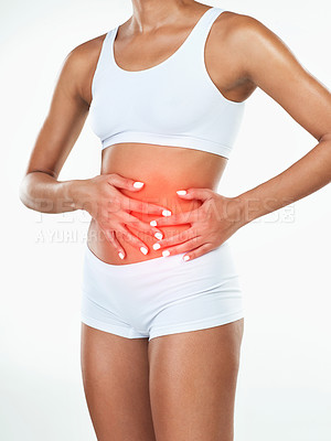 Buy stock photo Studio shot of an unrecognizable woman holding her tummy while standing against a white background