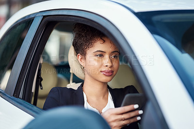Buy stock photo Cropped shot of an attractive young businesswoman using a smartphone while sitting in her car
