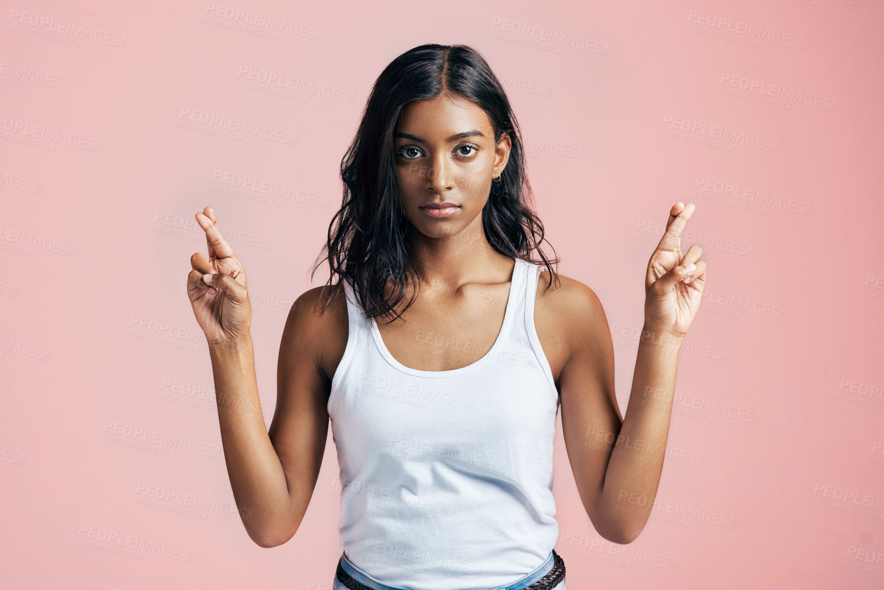 Buy stock photo Studio portrait of a beautiful young woman crossing her fingers against a pink background