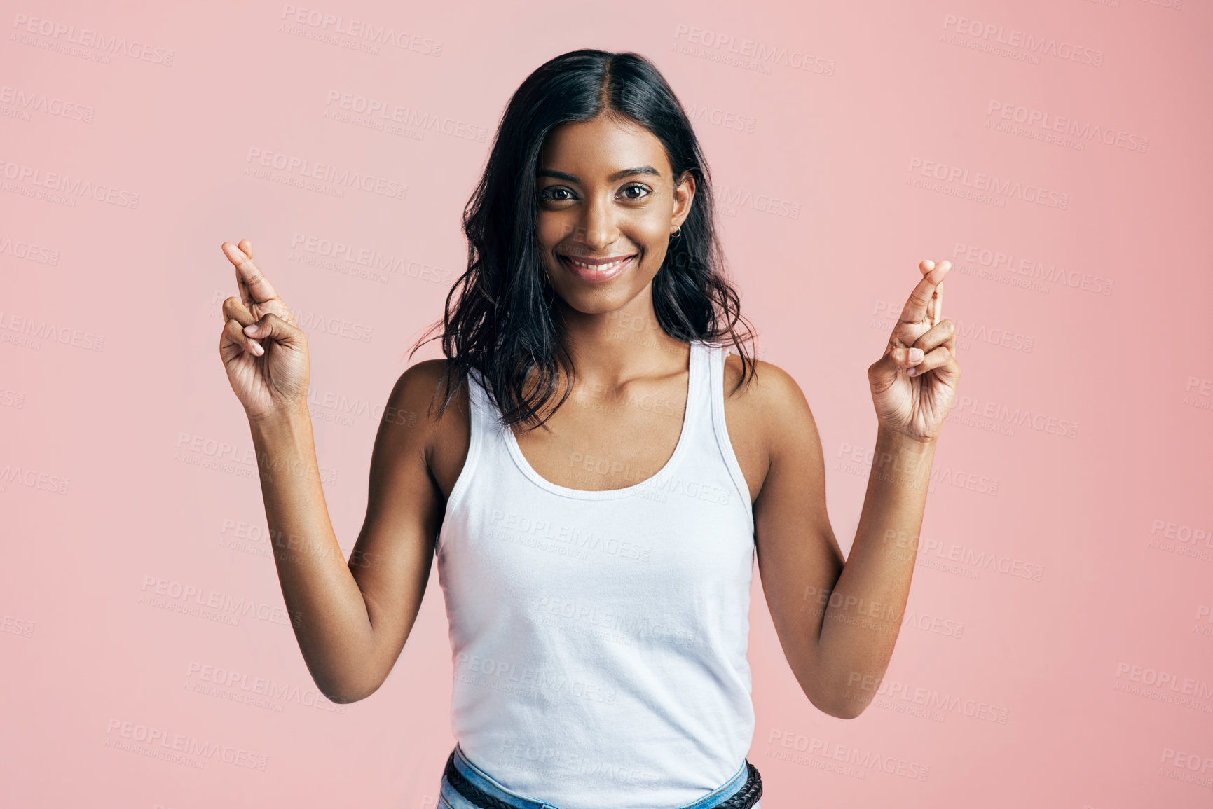 Buy stock photo Studio portrait of a beautiful young woman crossing her fingers against a pink background