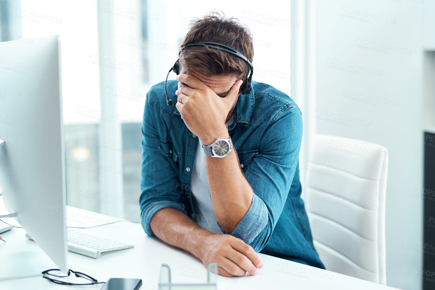 Buy stock photo Shot of a male call centre agent suffering from a headache in his office