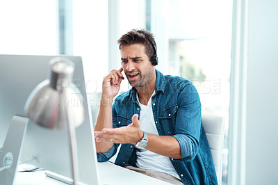 Buy stock photo Shot of a young call centre agent looking upset while working in his office
