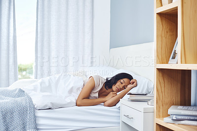 Buy stock photo Shot of a young woman sleeping peacefully in her bed at home