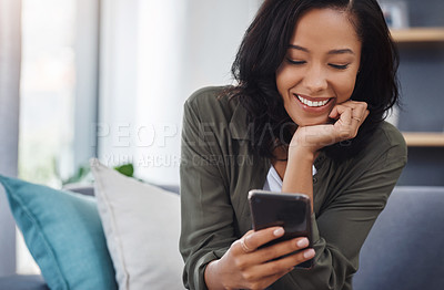 Buy stock photo Shot of an attractive young woman using a smartphone on the sofa at home