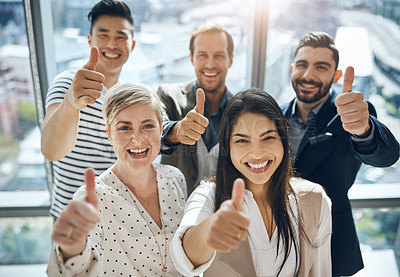 Buy stock photo Portrait of a group of confident young businesspeople standing together while showing thumbs up inside of the office during the day