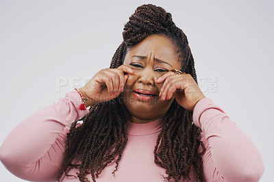 Buy stock photo Studio shot of a young woman crying while standing against a gray background