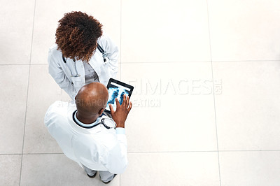 Buy stock photo High angle shot of two medical practitioners looking at x-ray scans on a digital tablet in a hospital