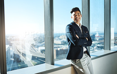 Buy stock photo Portrait of a young businessman standing at a window in an office