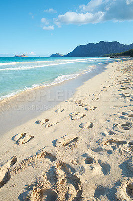 Buy stock photo Ocean, sand and travel with footprints at beach for summer vacation, adventure or tropical island. Journey, waves and cloud with steps in nature for holiday destination,  mountain and view with space