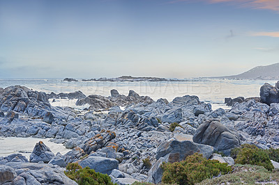 Buy stock photo Rocky coastline against blue horizon at sunset in South Africa. Peaceful and scenic landscape of boulders in the calm ocean water near Cape Town. Quiet location for vacation or nature walk in summer