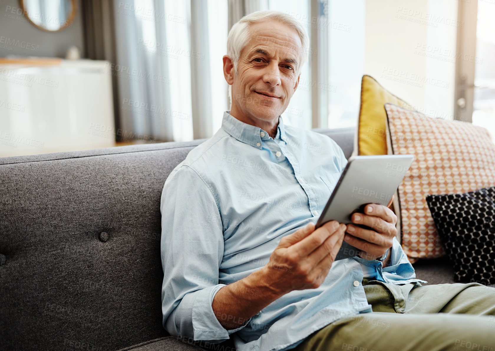 Buy stock photo Shot of a senior man relaxing and using a digital tablet on the sofa at home