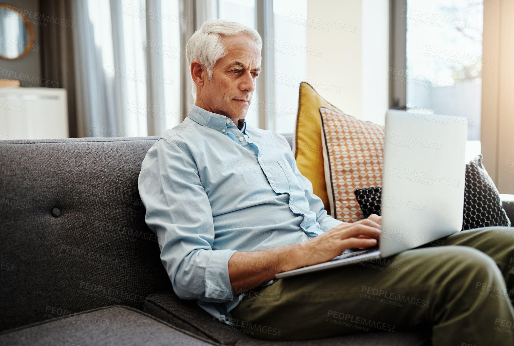 Buy stock photo Shot of a senior man relaxing and using a laptop on the sofa at home