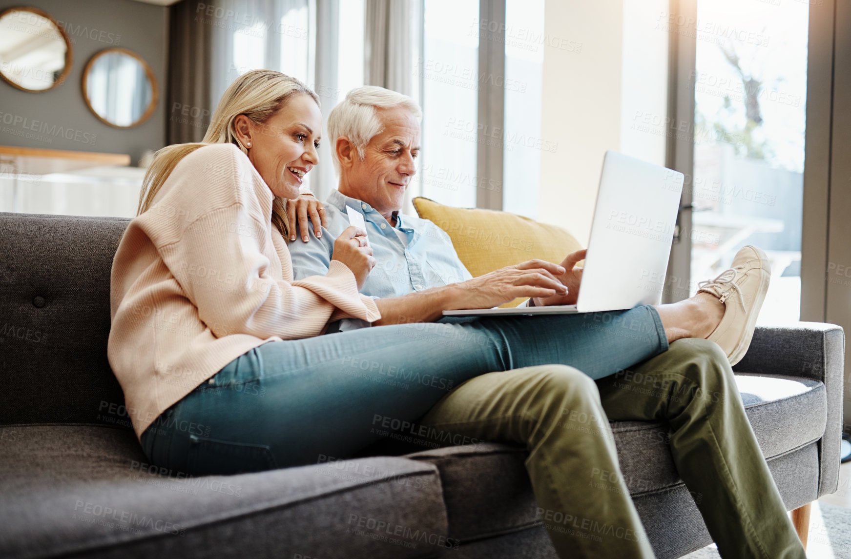 Buy stock photo Shot of a mature couple using a credit card and laptop on the sofa at home