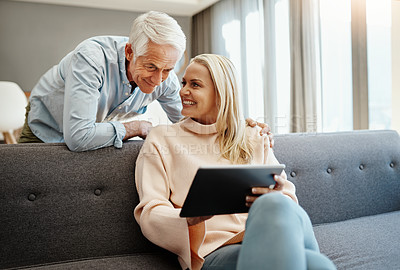Buy stock photo Shot of a mature couple using a digital tablet on the sofa at home