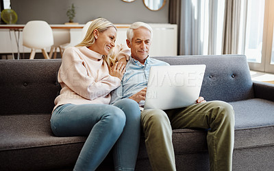 Buy stock photo Shot of a mature couple using a laptop on the sofa at home
