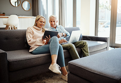 Buy stock photo Shot of a mature couple using a digital tablet and laptop on the sofa at home