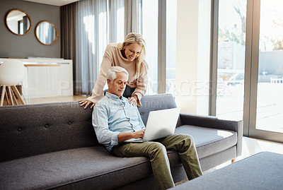 Buy stock photo Shot of a mature couple using a laptop on the sofa at home