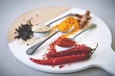 Buy stock photo Board, spices and spoon in gray background for curry, flavor and sensory appeal for creativity with culinary. Studio, condiment and seasoning for cooking with powder, aroma and ingredients collection