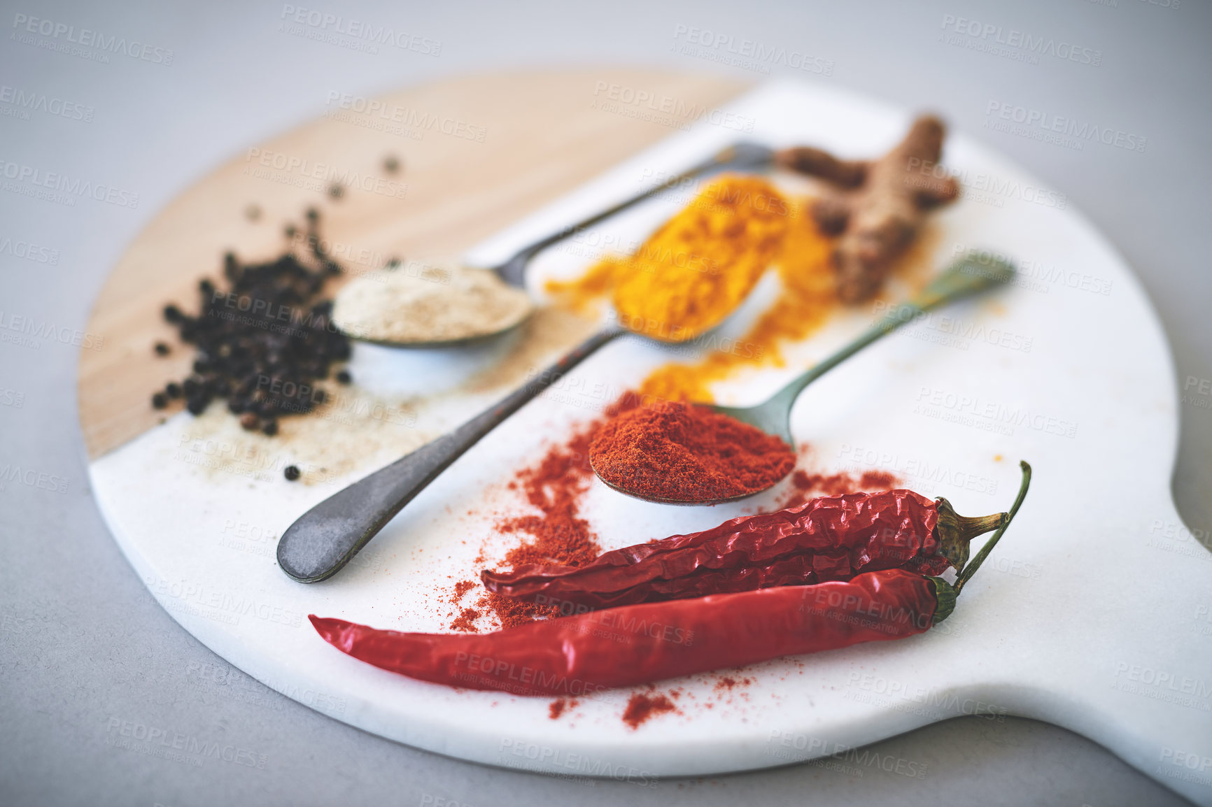 Buy stock photo Board, spices and spoon in gray background for curry, flavor and sensory appeal for creativity with culinary. Studio, condiment and seasoning for cooking with powder, aroma and ingredients collection