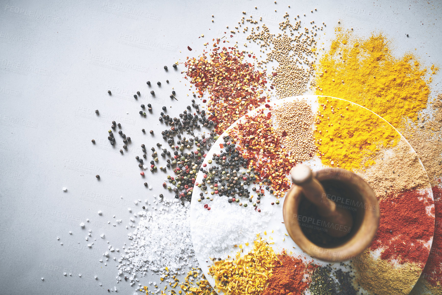 Buy stock photo Mortar, pestle and spices in white background for condiment, flavor and sensory appeal for creativity. Studio, organic herbs and seasoning for cooking with curry, powder and ingredients for culinary
