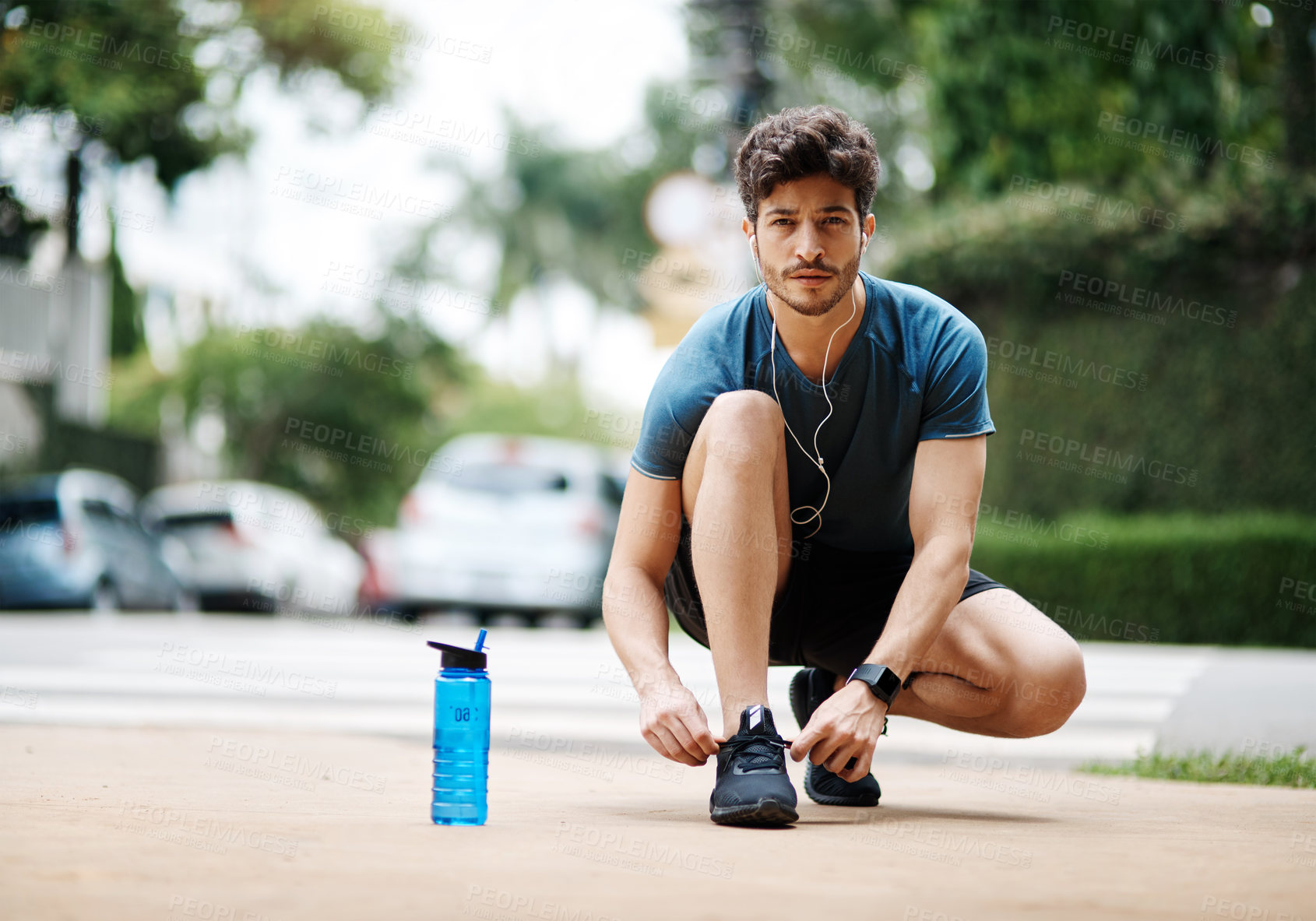 Buy stock photo Shot of a sporty young man tying his shoes before going for a jog outside during the day