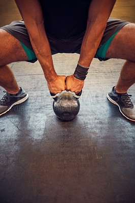 Buy stock photo Cropped shot of an unrecognizable young man working out with a kettle bell in the gym