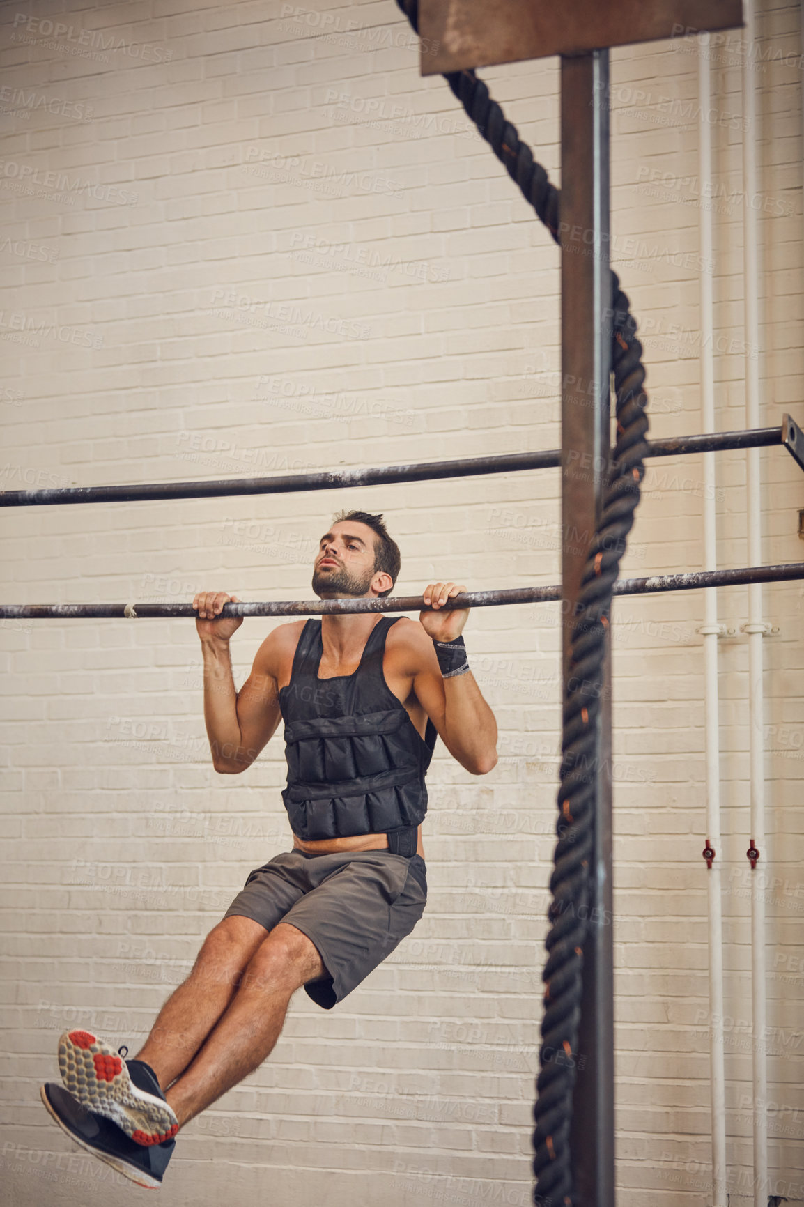 Buy stock photo Full length shot of a handsome young man doing pulls while working out in the gym