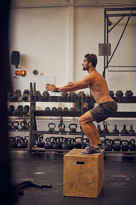 Buy stock photo Full length shot of a handsome young man box jumping while working out in the gym