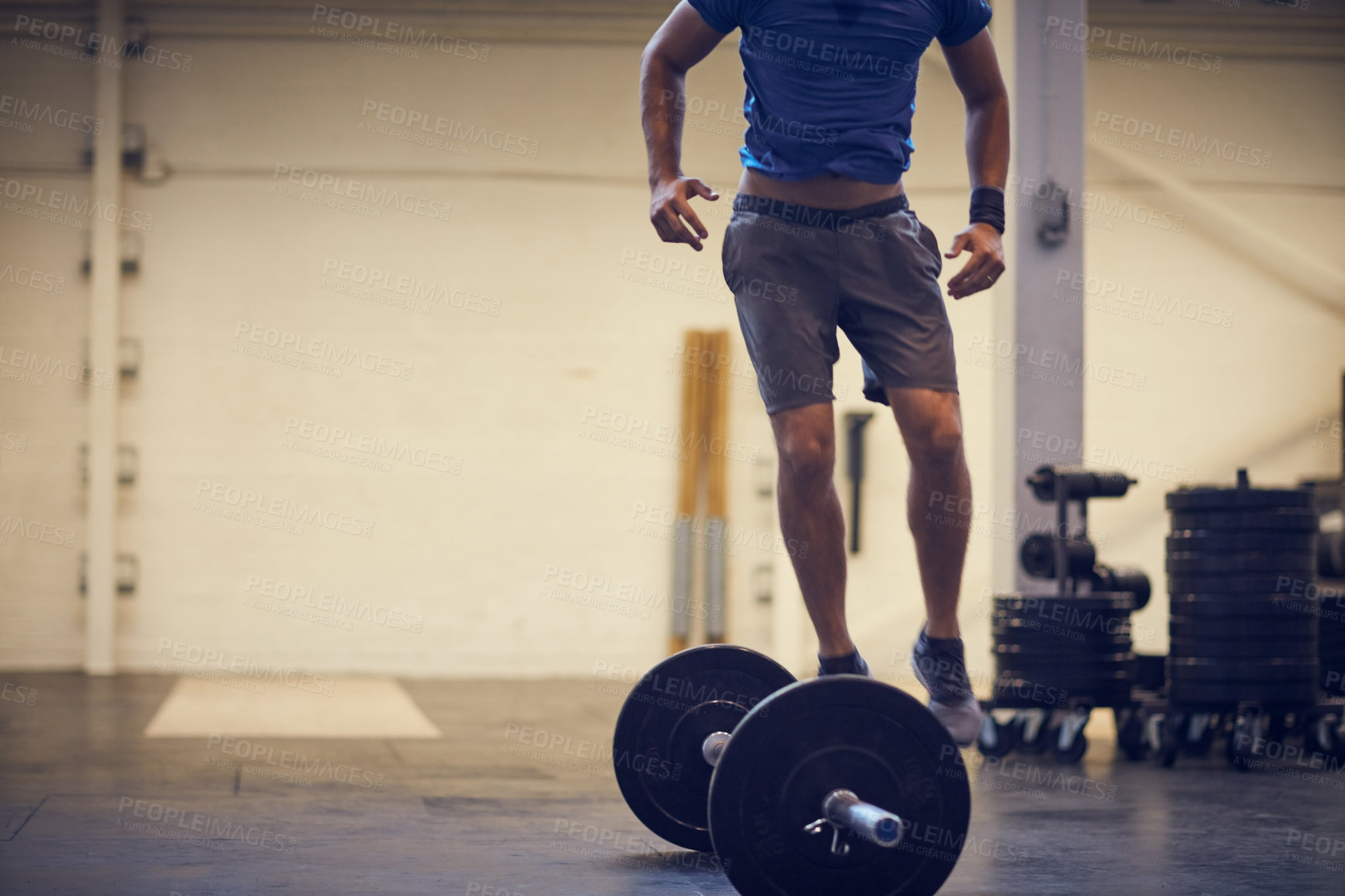 Buy stock photo Full length shot of an unrecognizable young man balancing on a barbell while working out in the gym