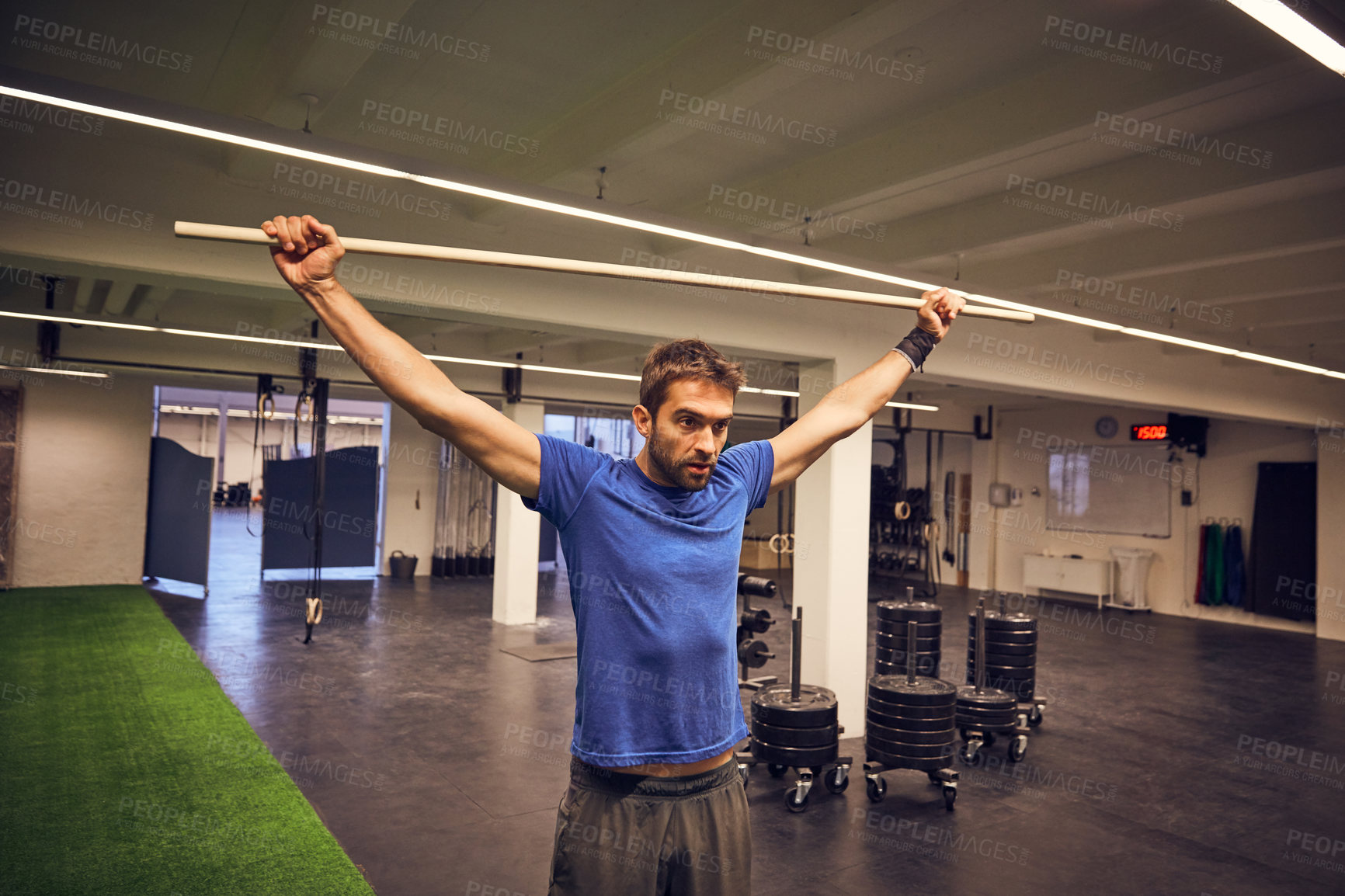 Buy stock photo Cropped shot of a handsome young man working out with a stick in the gym