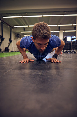 Buy stock photo Full length shot of a handsome young man doing pushups while working out in the gym