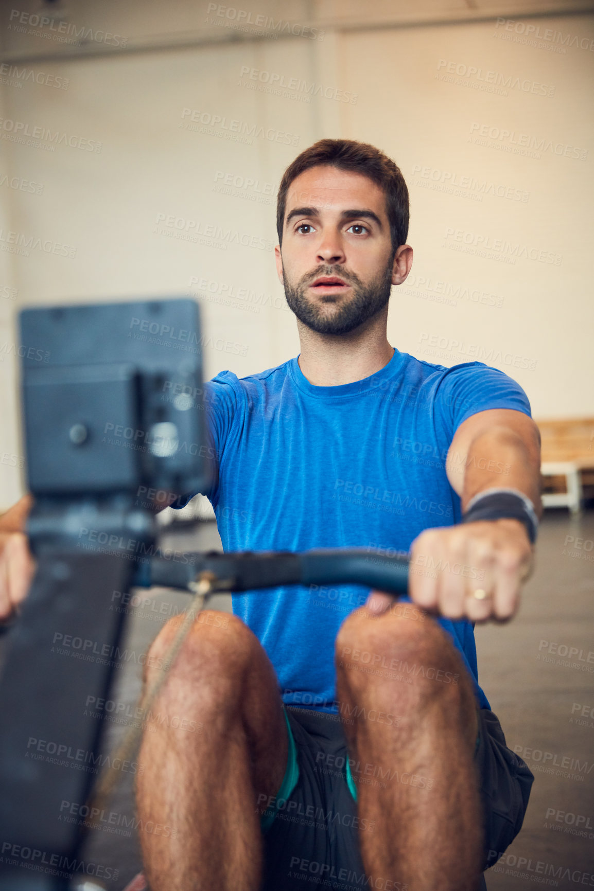 Buy stock photo Cropped shot of a handsome young man working out on a rowing machine in the gym