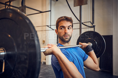 Buy stock photo Cropped shot of a handsome young man lifting weights while working out in the gym