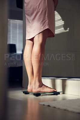 Buy stock photo Shot of an unrecognizble woman weighing herself on a scale at home