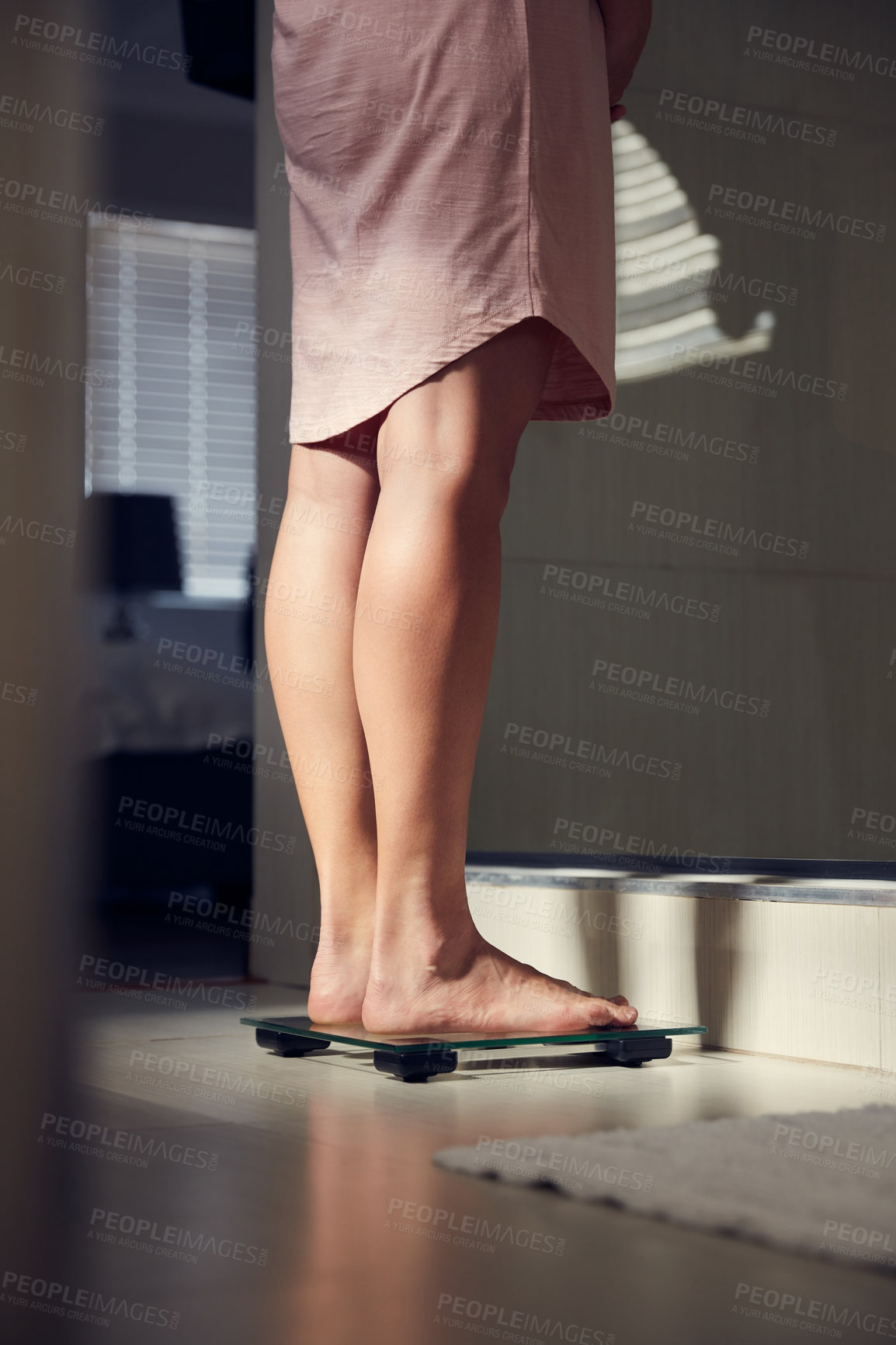 Buy stock photo Shot of an unrecognizble woman weighing herself on a scale at home