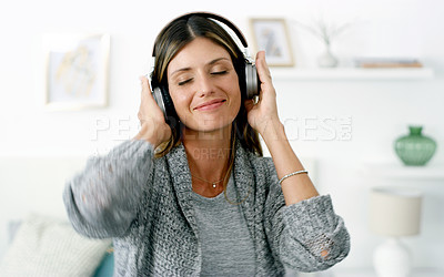 Buy stock photo Shot of a woman listening to music while relaxing at home