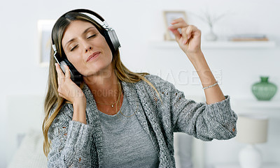 Buy stock photo Shot of a woman listening to music while relaxing at home