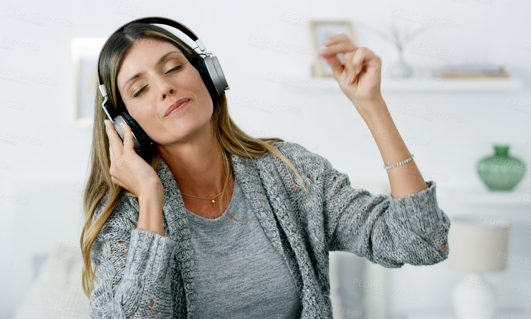 Buy stock photo Shot of a woman listening to music while relaxing at home
