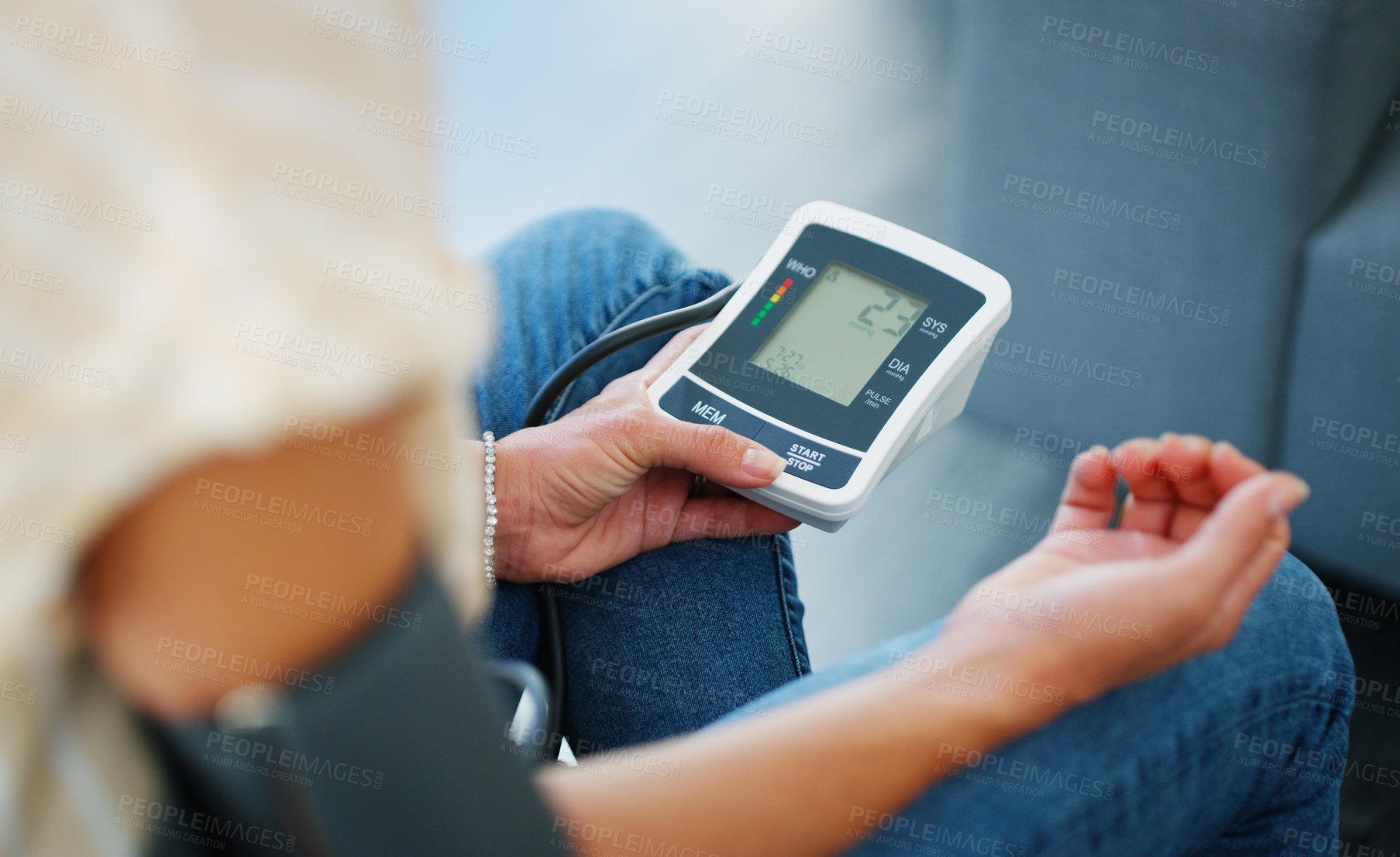 Buy stock photo Cropped shot of a woman checking her blood pressure at home