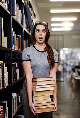 Buy stock photo Shot of a young woman looking surprised while carrying books in a library at college