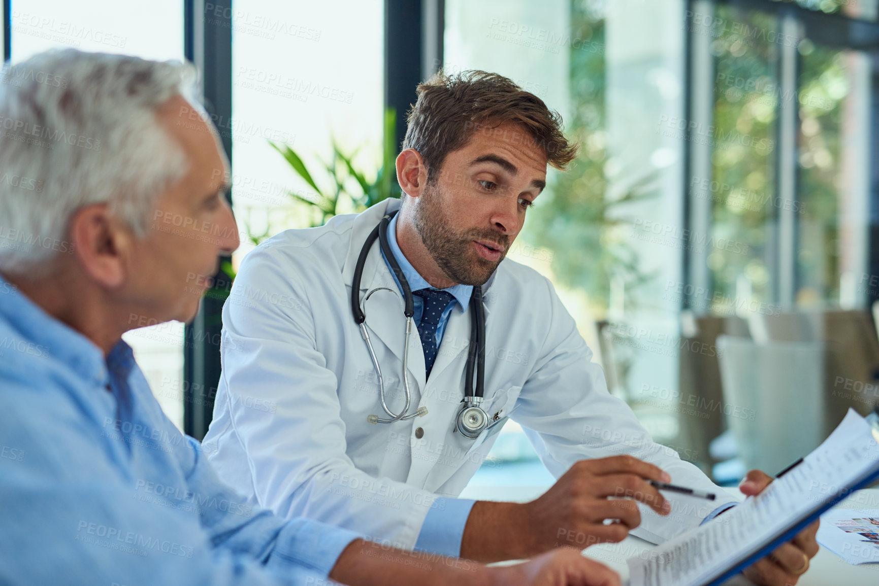 Buy stock photo Hospital, doctor and men with clipboard in consultation for health insurance, planning or feedback. People, patient and discussion with checklist at desk for coverage option, info or medical benefits