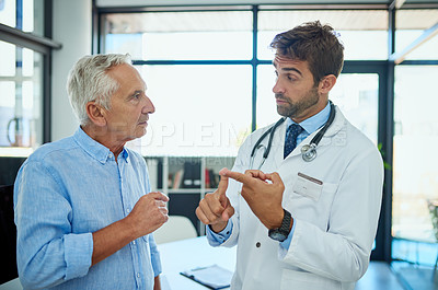 Buy stock photo Shot of a doctor consulting a male senior patient in his office