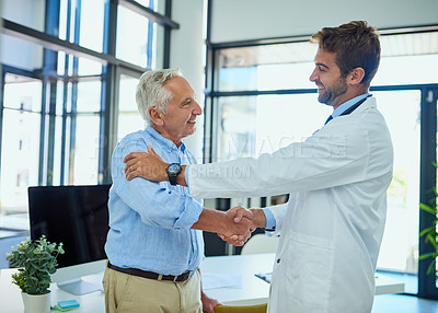 Buy stock photo Shot of a cheerful senior man shaking hands with his doctor in a clinic
