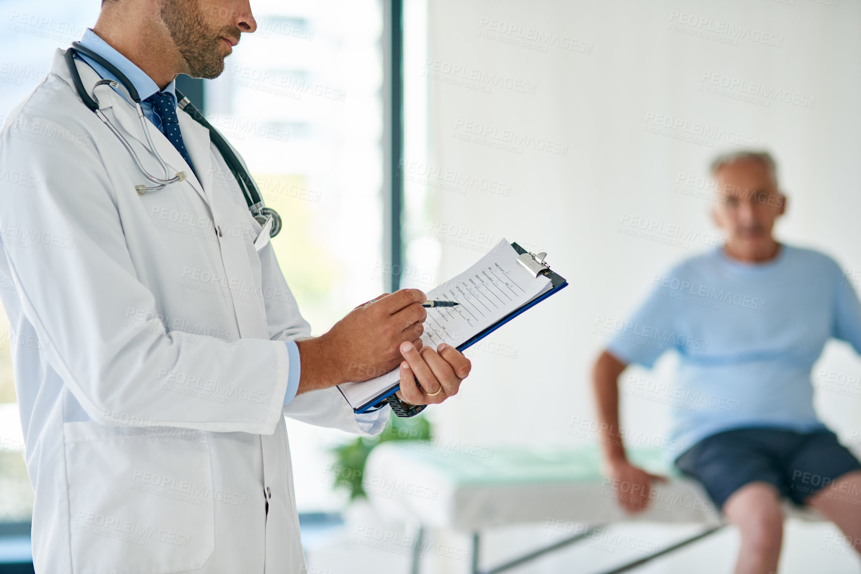 Buy stock photo Cropped shot of an unrecognizable young doctor filling out a file with his elderly patient in the background